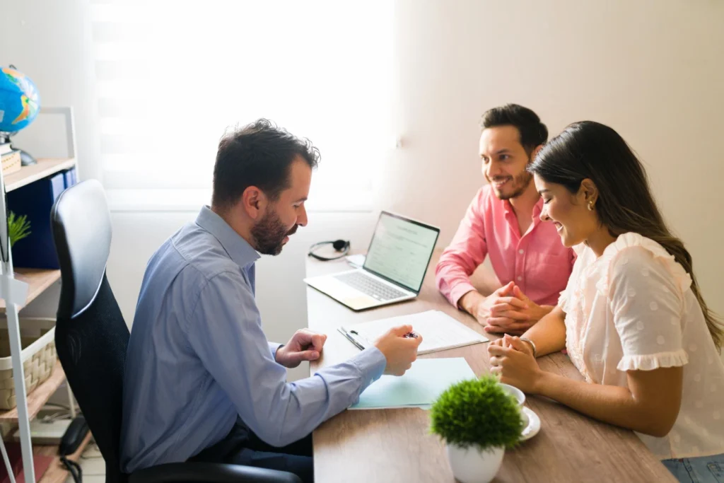 Financial advisor explaining document to smiling young couple in office.