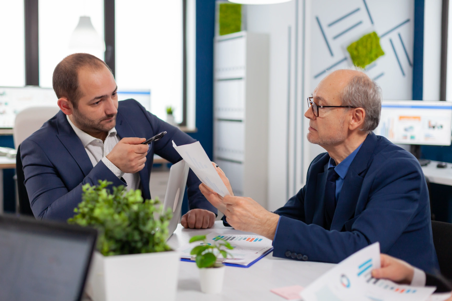 senior-entrepreneur-discussing-with-coworker-holding-documents-conference-briefing-businessman-discussing-ideas-with-colleagues-about-financial-strategy-new-start-up-company